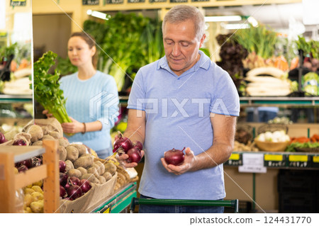 Aged man purchaser buying red onions in grocery store 124431770