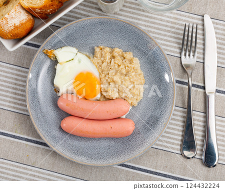 Continental breakfast for one person - portion of oatmeal, fried egg and sausage 124432224