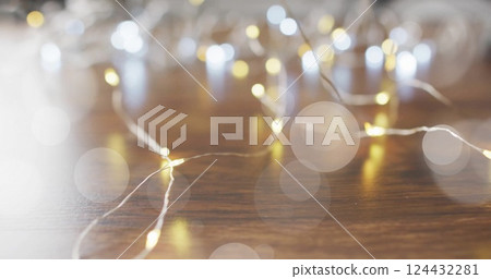 Fairy lights glowing over bokeh image on wooden surface Fairy lights glowing over bokeh image on wooden surface 124432281