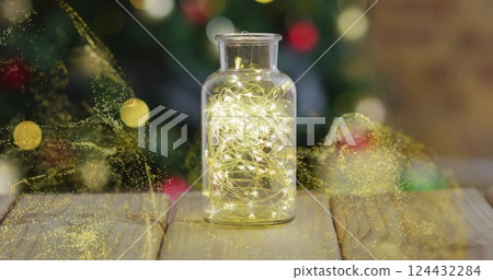 Glowing yellow particles image over jar with lights on wooden surface Glowing yellow particles image over jar with lights on wooden surface 124432284