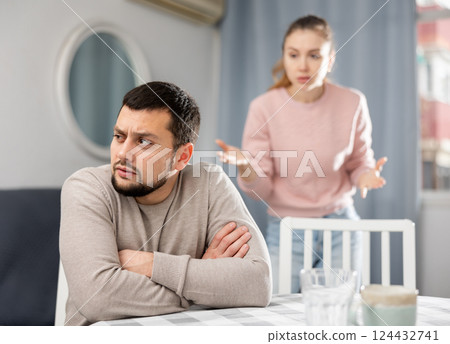 Offended man sitting at table with disgruntled woman behind 124432741