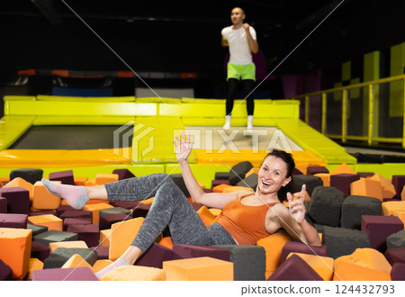Happy woman jumping into foam cube pit at indoor trampoline park 124432793