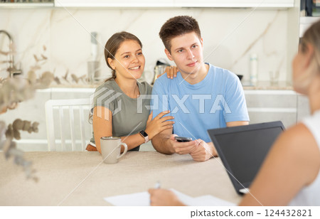 Couple of clients listen attentively and intently to woman of seller, who tells about advantages of making microloan in credit institution 124432821