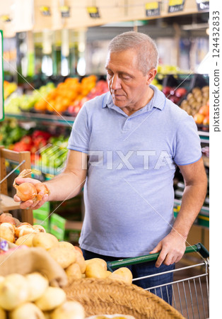 Serious mature male buyer buying onion in hypermarket Serious mature male buyer buying onion in hypermarket 124432833
