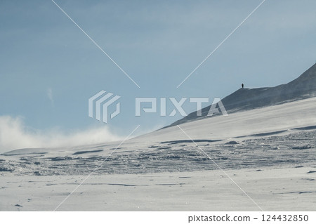 Snow smoke falling on the mountainside; steep ridges of snowy mountains; climbing snowy mountains in March Snow smoke falling on the mountainside; steep ridges of snowy mountains; climbing snowy mountains in March 124432850