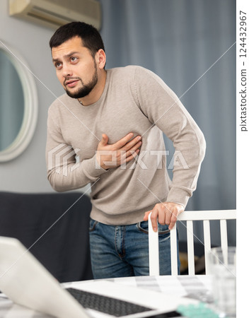 Man experiencing chest pain after working long hours on laptop Man experiencing chest pain after working long hours on laptop 124432967