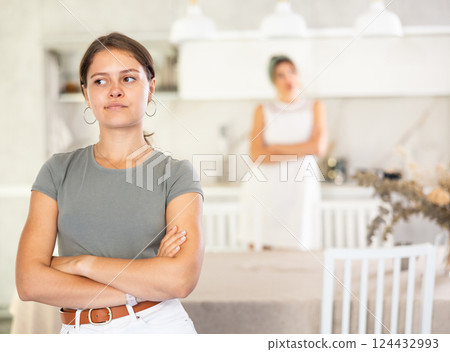 Young girl standing at the table while woman is quarreling with her standing behind 124432993