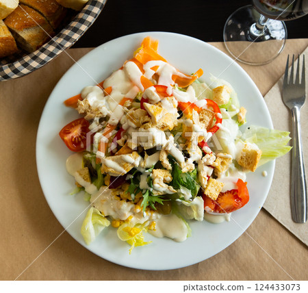 Caesar salad with chicken pieces, tomatoes on a white plate Caesar salad with chicken pieces, tomatoes on a white plate 124433073