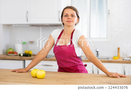 Young woman in apron posing in kitchen Young woman in apron posing in kitchen 124433076