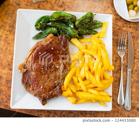 Grilled beef garnished with French fries and baked green pepper. 124433080