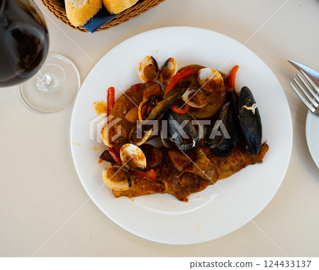 Hake in sailor style - fish cooked in thick tomato sauce with addition of mussels and shrimp Hake in sailor style - fish cooked in thick tomato sauce with addition of mussels and shrimp 124433137