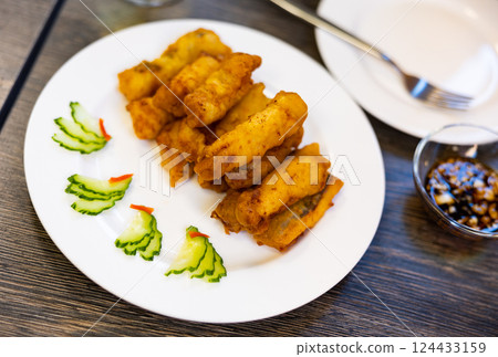 Pieces of eel fillet, fried to crispy crust, garnished with cucumber slices. 124433159