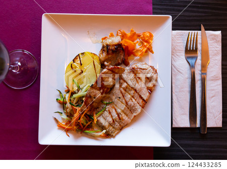 Tasty baked pork served with french fries and vegetables 124433285