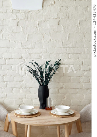 An Elegant Minimalist Dining Setup Featuring a Beautiful Vase and Carefully Arranged Plates 124433476