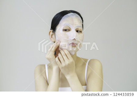 Young woman applying sheet mask 124433859