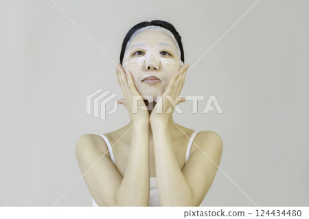 Young woman applying sheet mask Young woman applying sheet mask 124434480
