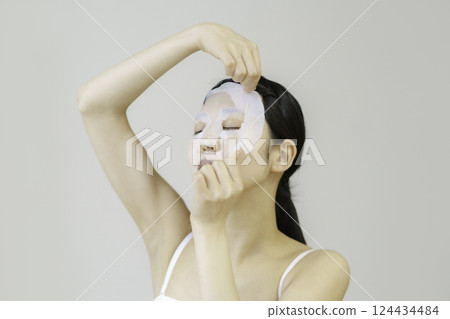 Young woman applying sheet mask Young woman applying sheet mask 124434484