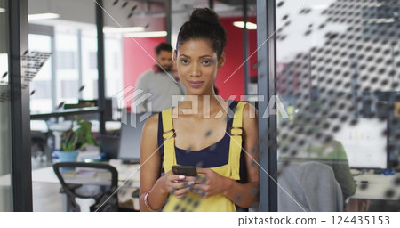 Image of world map over happy biracial businesswoman using smartphone at casual office 124435153