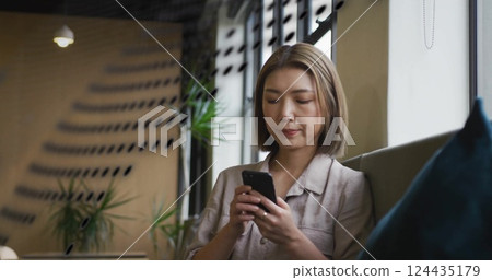 Image of data stream over asian businesswoman using smartphone at casual office lounge 124435179