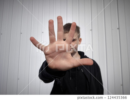 young caucasian guy wearing black sweater over white background shows stop sign prohibition symbol keeps palm forward to camera with strict expression 124435366