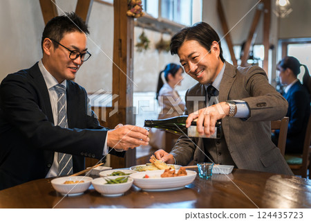 一位微笑的商人在酒吧/居酒屋為老闆或同事倒飲料 124435723
