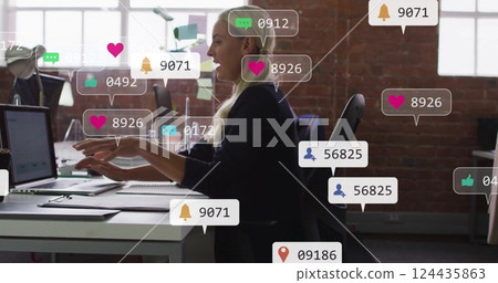 Social media notifications image over woman working at desk in office Social media notifications image over woman working at desk in office 124435863