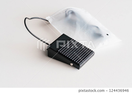 Black Foot Pedal Switch with Cable and White Plastic Packaging on Neutral Background 124436946