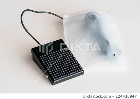 Black Foot Pedal Switch with Attached Cable Inside Transparent Plastic Bag on White Surface Black Foot Pedal Switch with Attached Cable Inside Transparent Plastic Bag on White Surface 124436947