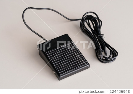 Black Industrial Footswitch Pedal with Cable on Beige Surface Black Industrial Footswitch Pedal with Cable on Beige Surface 124436948