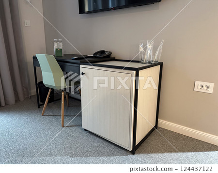 Work corner with desk and television in modern hotel room interior. Business travel, functionality, order, and minimalist contemporary workspace design. 124437122
