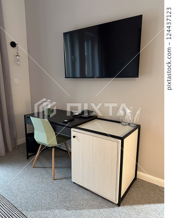 Work corner with desk and television in modern hotel room interior. Business travel, functionality, order, and minimalist contemporary workspace design. Work corner with desk and television in modern hotel room interior. Business travel, functionality, order, and minimalist contemporary workspace design. 124437123