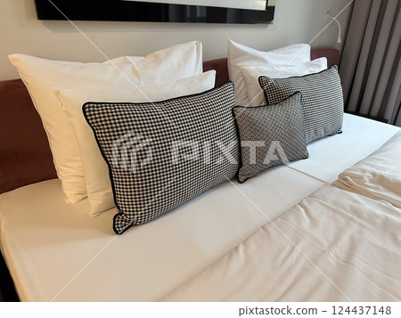 Double bed in bright hotel room with elegant textiles and window view. Hospitality, comfort, rest, and vacation in a modern, cozy interior space. Double bed in bright hotel room with elegant textiles and window view. Hospitality, comfort, rest, and vacation in a modern, cozy interior space. 124437148