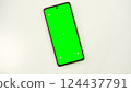 Mobile phone with green screen lies on white surface. Mobile phone mockup. Social media advertising concept, trading platforms. Smartphone with chromakey. Close-up. Plenty of space for your text. 124437791