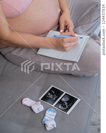 Pregnant woman takes notes in a notebook. Pregnant woman takes notes in a notebook. 124437834