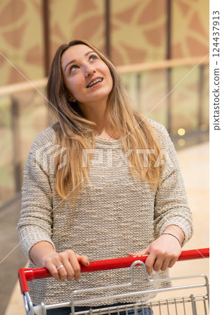 Caucasian woman with braces pushing shopping cart. Caucasian woman with braces pushing shopping cart. 124437913