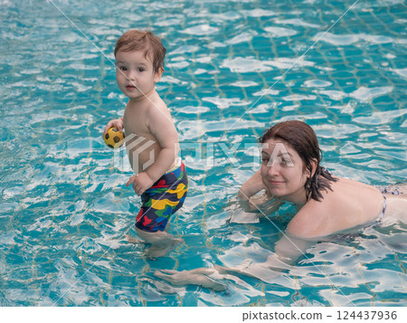 A Caucasian woman and her one-year-old son swim in a pool. 124437936