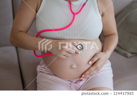 A pregnant woman listens to her baby's pulse using a phonendoscope. 124437985