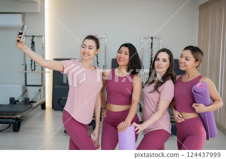 Two Caucasian and two Asian women take a selfie after a Pilates workout.  124437999