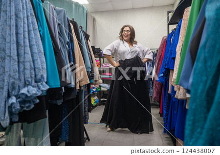 A fat woman chooses clothes in a plus size store.  124438007