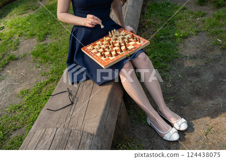Caucasian woman playing chess outdoors. Caucasian woman playing chess outdoors. 124438075