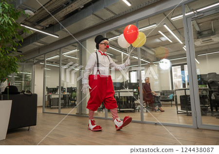 Elderly man in clown costume with balloons in office. Elderly man in clown costume with balloons in office. 124438087