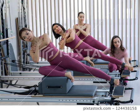 A trainer adjusts women on a reformer. 124438158
