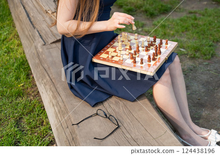 Caucasian woman playing chess outdoors. Caucasian woman playing chess outdoors. 124438196