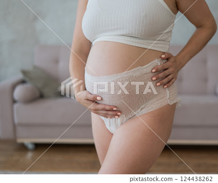 Caucasian pregnant woman in adult diapers suffers from incontinence. Close-up of belly.  124438262