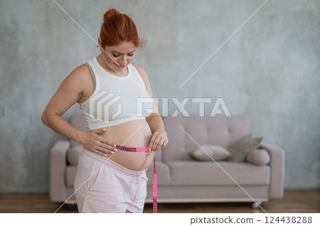 Pregnant woman measuring her belly.  124438288
