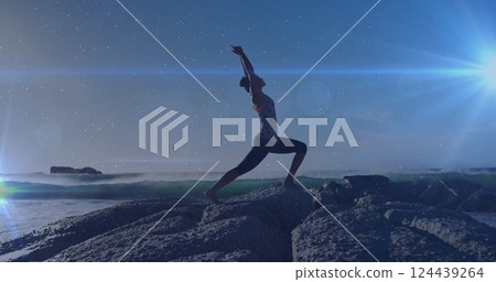 Image of light spots over biracial woman practicing yoga at beach Image of light spots over biracial woman practicing yoga at beach 124439264