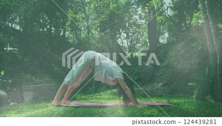 Image of light spots over caucasian woman practicing yoga in garden 124439281