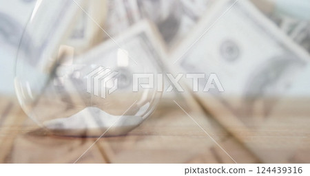 Image of multiple banknotes over hourglass Image of multiple banknotes over hourglass 124439316