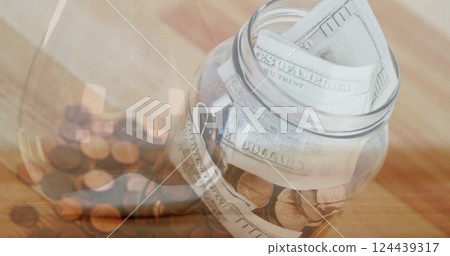 Image of jar of banknotes and coins over hourglass Image of jar of banknotes and coins over hourglass 124439317