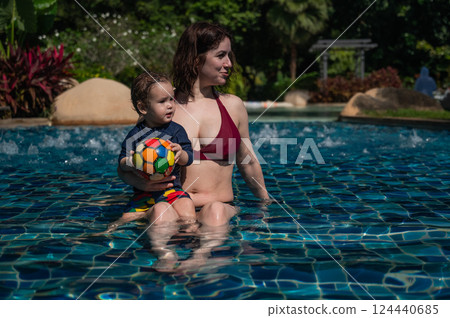 A Caucasian woman and her one-year-old son swim in a pool. A Caucasian woman and her one-year-old son swim in a pool. 124440685